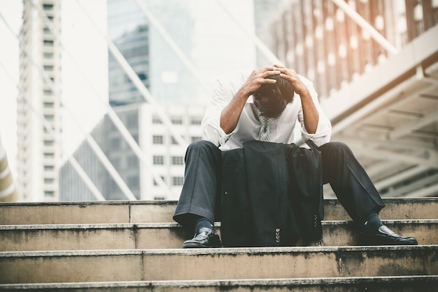 Homme d&#39;affaires fatigué ou stressé assis sur la passerelle de la ville après son travail.