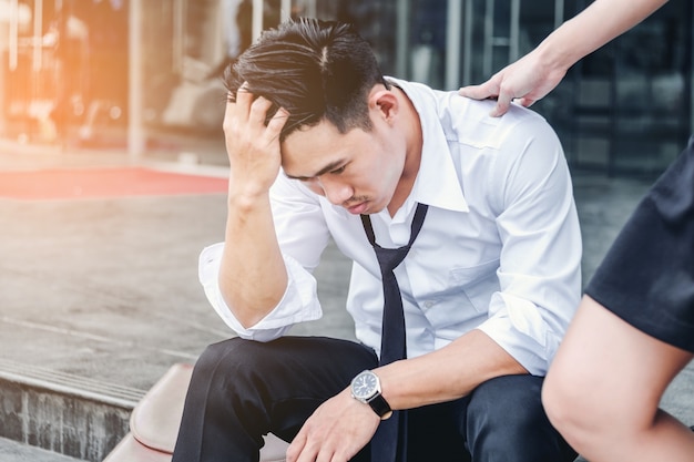 Homme d&#39;affaires fatigué ou stressé assis sur le trottoir après le travail