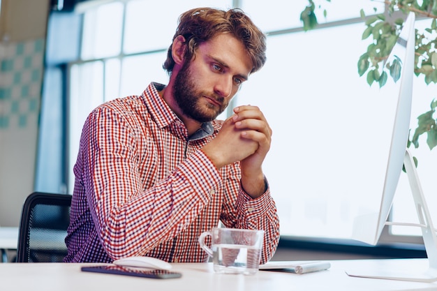 Homme d'affaires fatigué travaillant sur son ordinateur en open space office