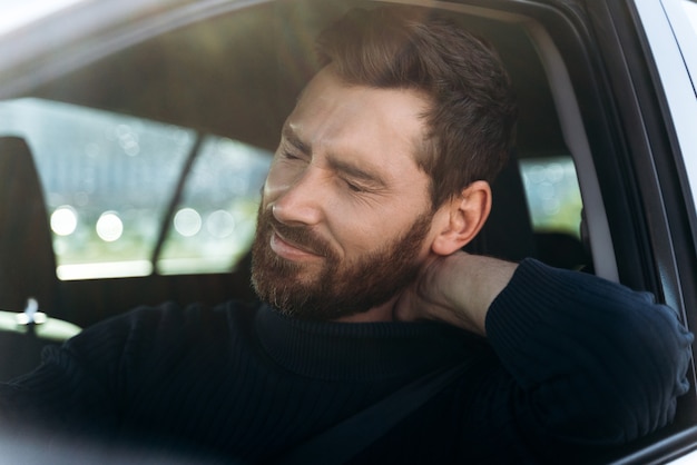 Homme d'affaires fatigué en voiture ressentant une forte douleur au cou et une inflammation des nerfs, après une longue route. Concept de problèmes de transport et de santé