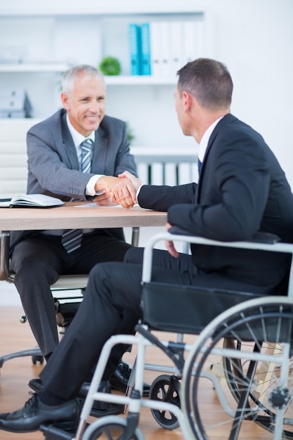 Homme d&#39;affaires en fauteuil roulant se serrant la main avec un collègue