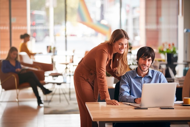 Homme d'affaires et femme d'affaires se réunissant par bureau dans un bureau moderne à plan ouvert