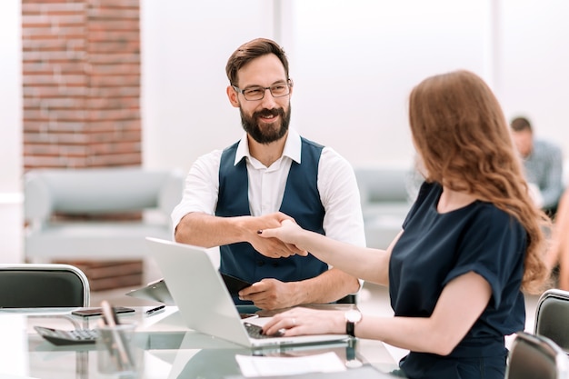 Homme d'affaires et femme d'affaires se serrant la main sur le bureau