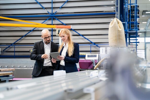 Homme d'affaires et femme d'affaires avec tablette discutant en usine