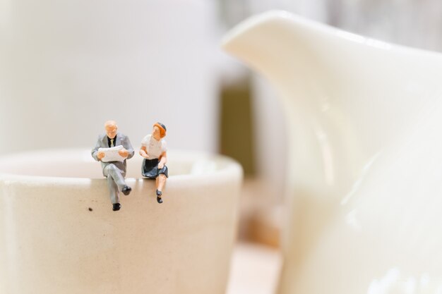 homme d&#39;affaires et femme assise sur une tasse de thé