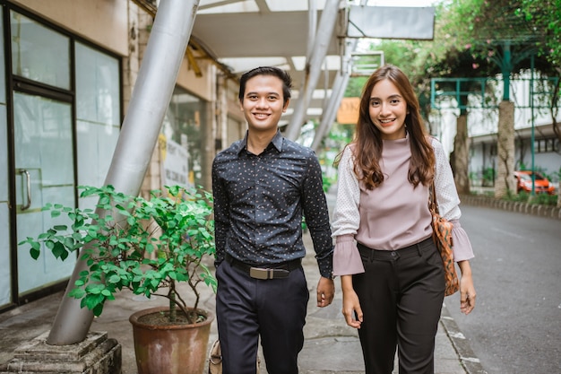 Homme d'affaires et femme marchant sur le trottoir souriant allant au bureau