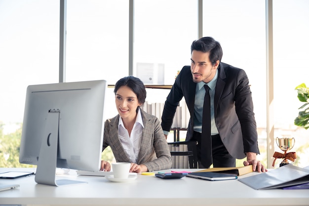 Homme d'affaires et femme à la recherche d'un ordinateur portable au bureau et heureux de réussir