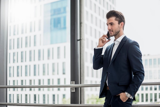 Homme d'affaires à la fenêtre sur téléphone portable