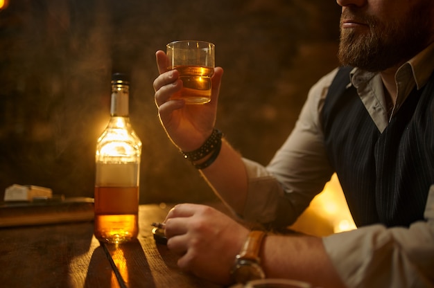 Homme d'affaires fume la cigarette et boit des boissons alcoolisées, intérieur de bureau vintage. Culture du tabagisme, saveur spécifique. Fumeur masculin