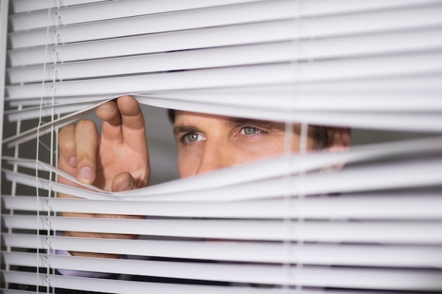 Homme d&#39;affaires furtivement à travers des stores au bureau