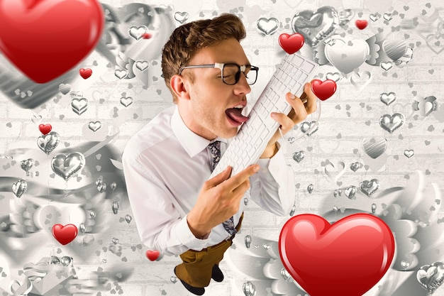 Homme d'affaires geek léchant son clavier contre le motif coeur gris de la Saint-Valentin