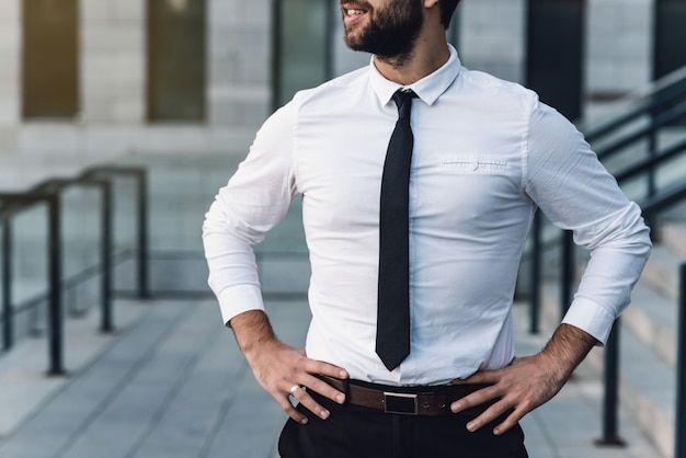 Homme d&#39;affaires de gros plan dans une chemise blanche sourit avec bonheur sur une journée ensoleillée. Tenant ses mains à