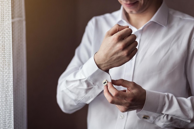 L'homme d'affaires habille les mains masculines de chemise blanche closeupgroom se prépare le matin avant la cérémonie de mariage