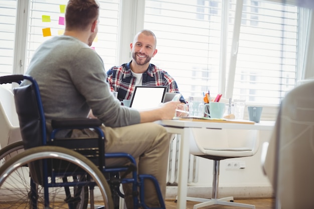 Photo homme d'affaires handicap discutant avec un collègue au bureau