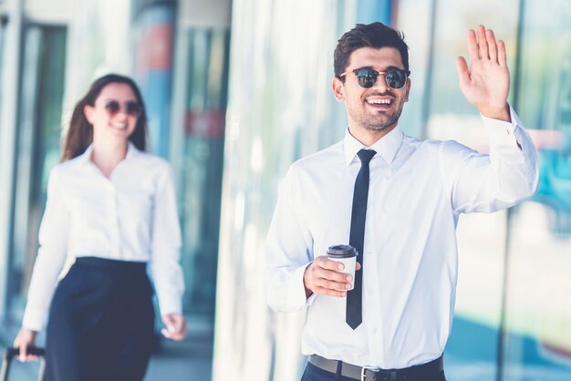 L'homme d'affaires heureux dans le geste de lunettes de soleil près de la femme