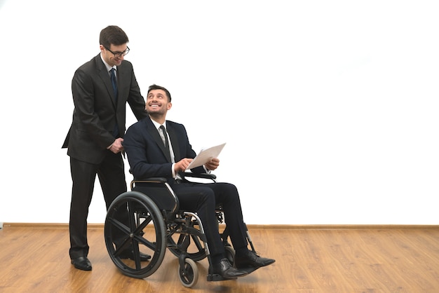 L'homme d'affaires heureux et l'invalide tiennent des papiers sur le fond du mur blanc