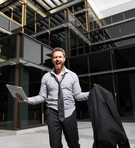 Homme d'affaires heureux réussi avec ordinateur et veste criant célébrant le succès de l'entreprise en plein air, bonheur.