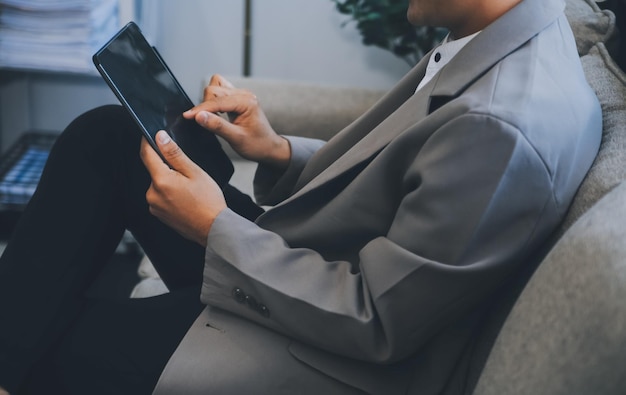 Un homme d'affaires heureux vêtu d'un costume dans un bureau moderne en utilisant une tablette