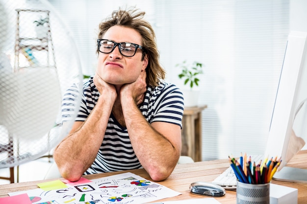 Photo homme d'affaires hipster assis devant un ventilateur et grimaçant dans son bureau