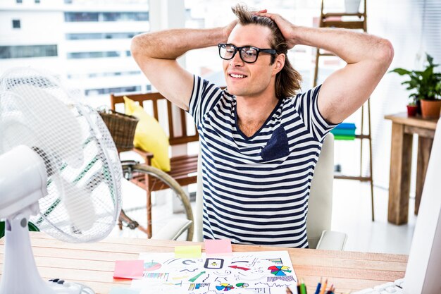 Photo homme d'affaires hipster assis devant un ventilateur à son bureau