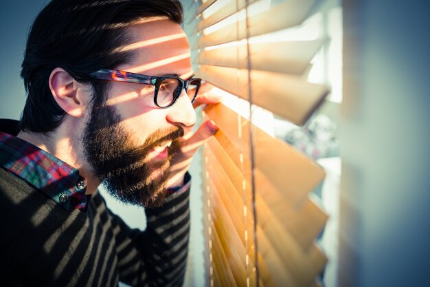 Homme D'affaires Hipster Furtivement à Travers Les Stores