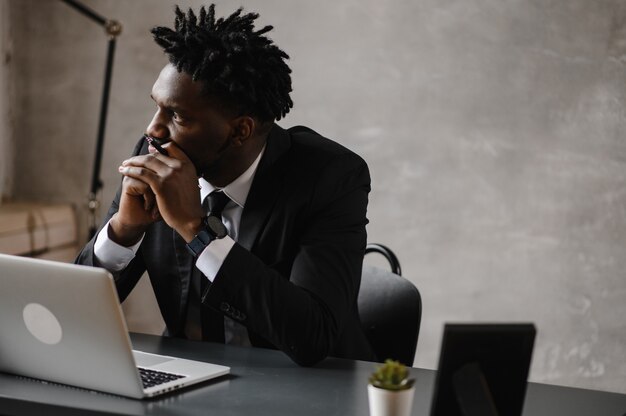 Homme d'affaires un homme afro-américain en costume travaille sur un ordinateur portable