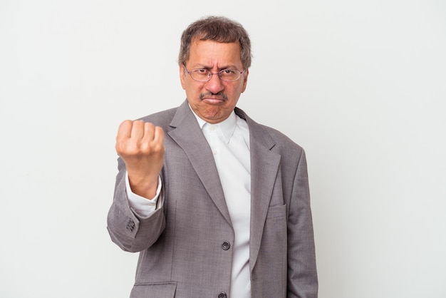 Homme d'affaires indien d'âge moyen isolé sur fond blanc montrant le poing à la caméra, expression faciale agressive.