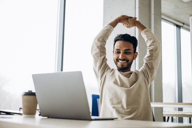 Homme d'affaires indien assis au bureau travaillant sur un ordinateur portable