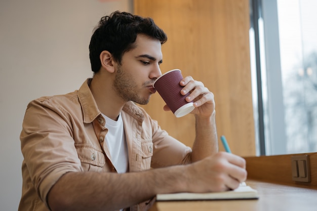 Homme d'affaires indien, boire du café au café, prendre des notes, planifier le démarrage