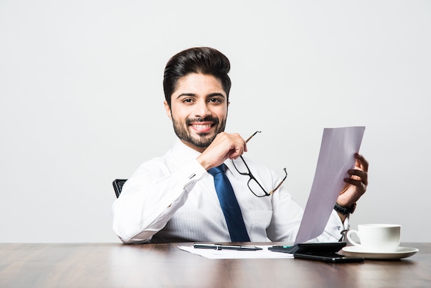 Homme d'affaires indien écrivant un document alors qu'il était assis au bureau ou au poste de travail