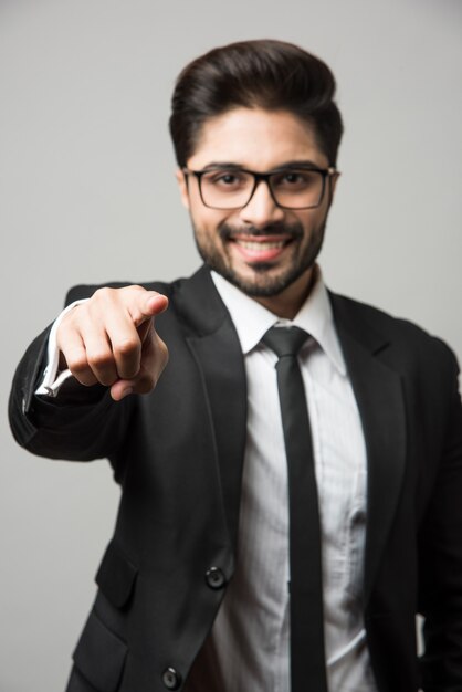 Homme d'affaires indien pointant sur vous, debout isolé sur fond blanc