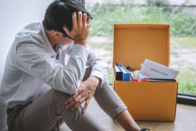 Un homme d'affaires inquiet avec une lettre de démission assis au bureau.