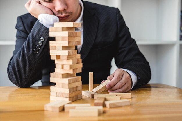 Un homme d'affaires inquiet et réfléchi tenant des blocs de bois à son bureau.