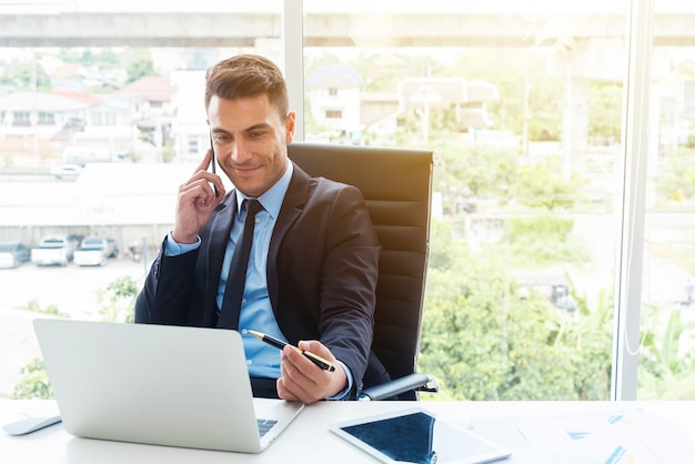 Homme d&#39;affaires intelligent utilisant mobile et ordinateur portable au bureau.