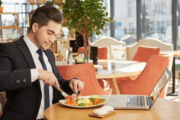 Homme d&#39;affaires jeune attractif prenant son petit déjeuner au café local