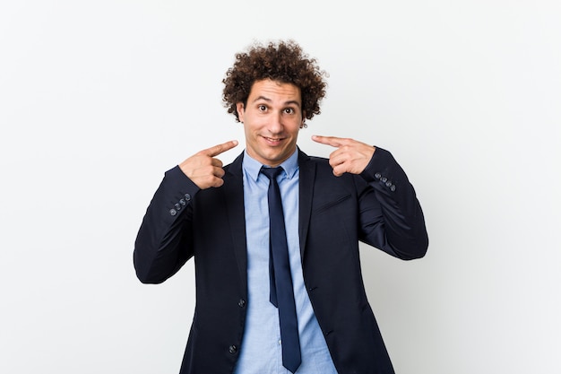 Homme d'affaires jeune bouclé sur des sourires blancs, pointant les doigts vers la bouche.