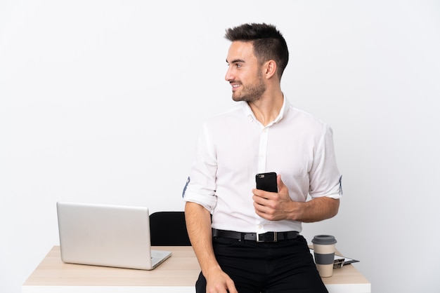 Homme d'affaires jeune avec un téléphone portable dans un lieu de travail à la recherche sur le côté