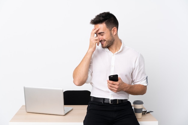 Homme d'affaires jeune avec un téléphone portable dans un lieu de travail en riant