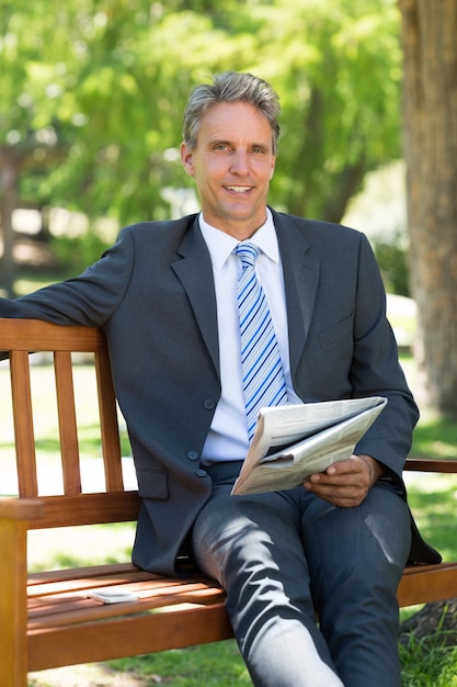 Homme d&#39;affaires avec journal assis dans le parc