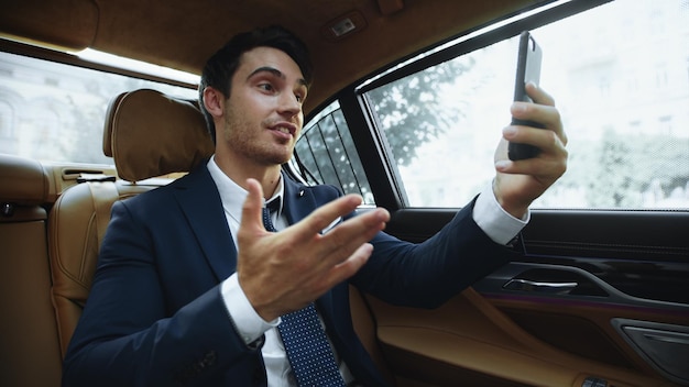 Photo homme d'affaires joyeux ayant un appel vidéo sur téléphone portable dans une voiture d'affaires