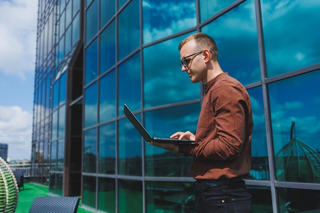 Un homme d'affaires joyeux habillé formellement satisfait d'avoir reçu de bonnes nouvelles sur les détails du contrat assis sur la terrasse du bureau avec un ordinateur portable entrepreneur masculin prospère