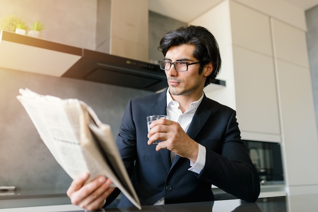 Homme d'affaires lire des nouvelles d'un journal tout en buvant un café à la maison