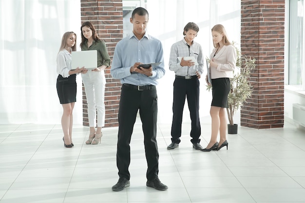 Homme d'affaires lisant un document debout dans le hall du bureau