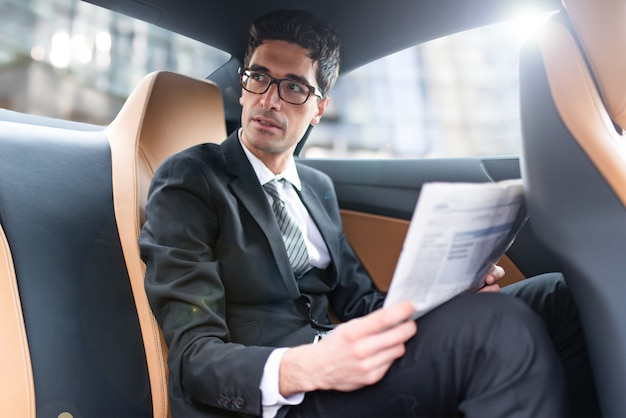 Homme d'affaires lisant un journal dans sa voiture Effet de lumière parasite