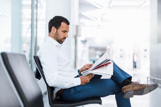 Homme d'affaires lisant un journal dans la salle d'attente