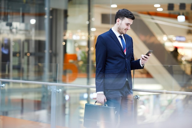 Homme d'affaires lisant des sms dans le hall