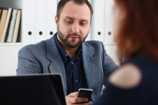 homme d'affaires lors d'une réunion à l'aide de son smartphone