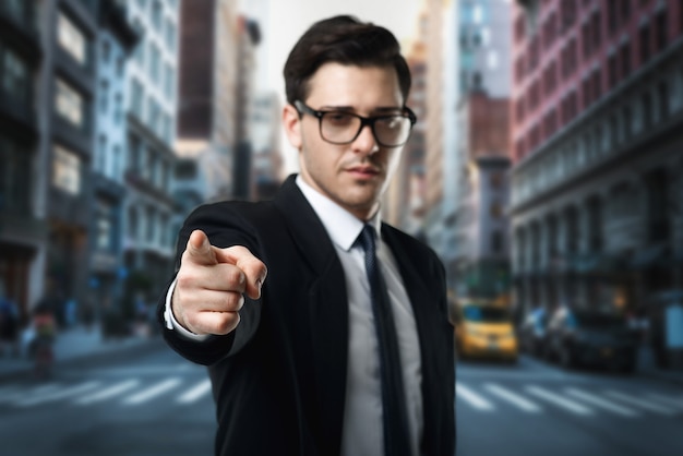 Homme d'affaires à lunettes, cravate et costume noir pointer un doigt sur la rue, centre d'affaires