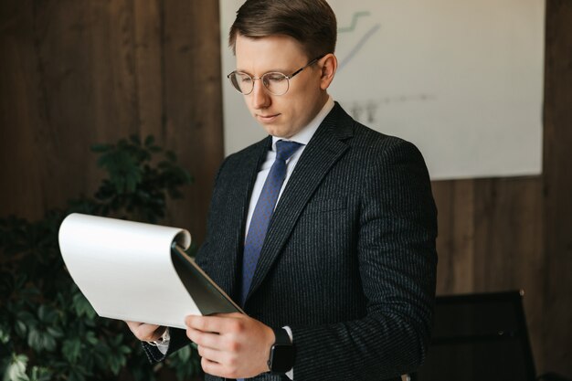 Homme d'affaires à lunettes examine les documents au bureau.