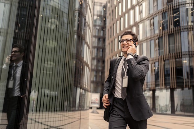 Un homme d'affaires avec des lunettes parle au téléphone va travailler au bureau